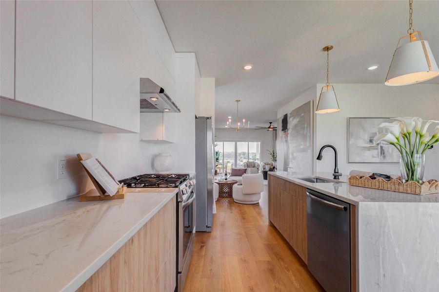 This beautifully designed kitchen offers a seamless blend of style and functionality, featuring sleek quartz countertops, modern cabinetry, and a spacious layout ideal for everyday living. The large island with integrated sink and seating provides the perfect gathering space, while stainless steel appliances and designer lighting elevate the overall look. Warm wood tones add contrast and sophistication throughout. The picture shown is from the model home with the same floor plan, Rev floor plan.