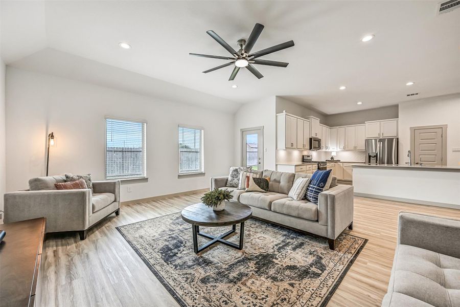 Abundant natural light fills the spacious family room through multiple rear-facing windows, while an oversized ceiling fan and neutral finishes complement the home's fresh contemporary style. Abundant natural light fills the spacious family room through multiple rear-facing windows, while an oversized ceiling fan and neutral finishes complement the home's fresh contemporary style.