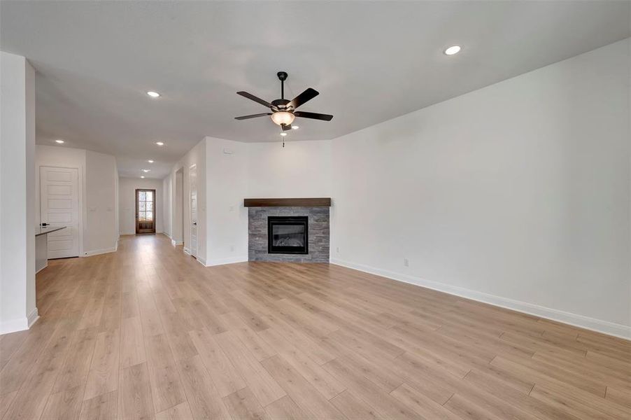 Unfurnished living room featuring recessed lighting, a fireplace, ceiling fan, and light wood finished floors
