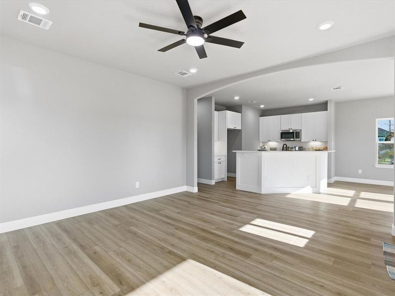 Unfurnished living room with recessed lighting, arched walkways, light wood finished floors, and a ceiling fan Unfurnished living room with recessed lighting, arched walkways, light wood finished floors, and a ceiling fan