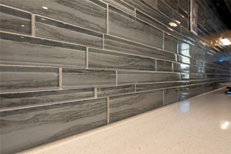 Elevate your culinary experience with the upgraded glass tiled backsplash, seamlessly blending with quartz counters and pristine white cabinets to make a bold statement in style.