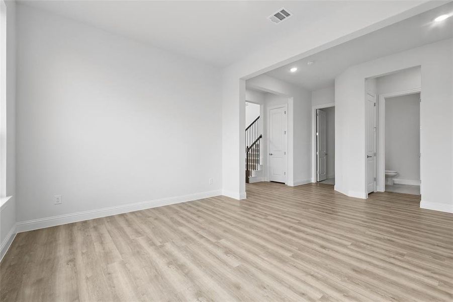 Unfurnished living room with visible vents, stairs, light wood-style floors, baseboards, and recessed lighting Unfurnished living room with visible vents, stairs, light wood-style floors, baseboards, and recessed lighting