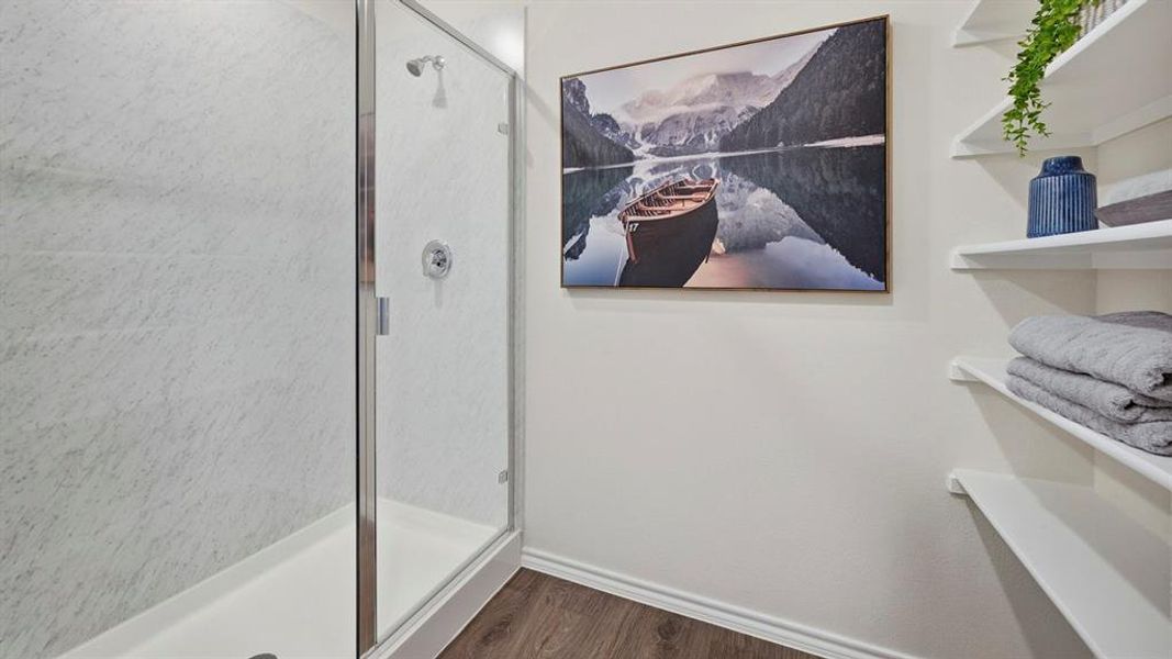 Bathroom featuring dark wood-style floors and a shower stall Bathroom featuring dark wood-style floors and a shower stall