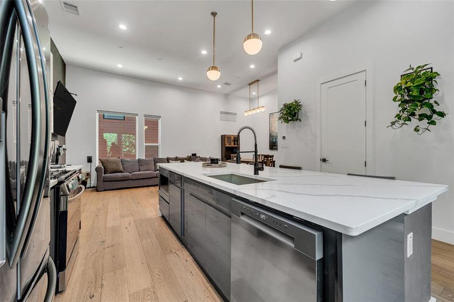 Kitchen featuring a center island with sink, decorative light fixtures, light wood-type flooring, stainless steel appliances, and recessed lighting Kitchen featuring a center island with sink, decorative light fixtures, light wood-type flooring, stainless steel appliances, and recessed lighting