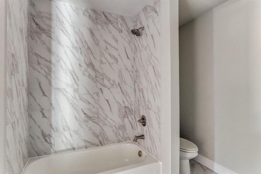 Full bath with bathtub / shower combination and marble look tile flooring