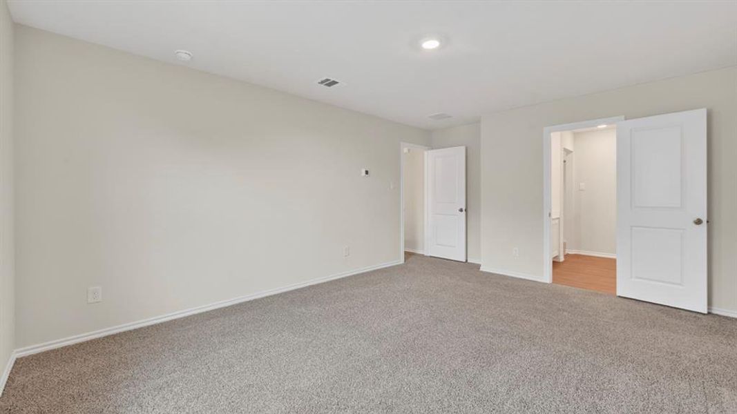Spacious room featuring gray carpeting, light-toned wall paint, recessed lighting, and white paneled interior doors