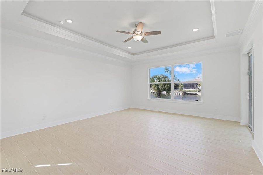 Spare room with a ceiling fan, wood finish floors, a tray ceiling, ornamental molding, and recessed lighting