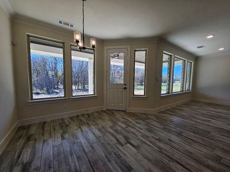 Unfurnished dining area with a chandelier, ornamental molding, plenty of natural light, and dark wood-style floors