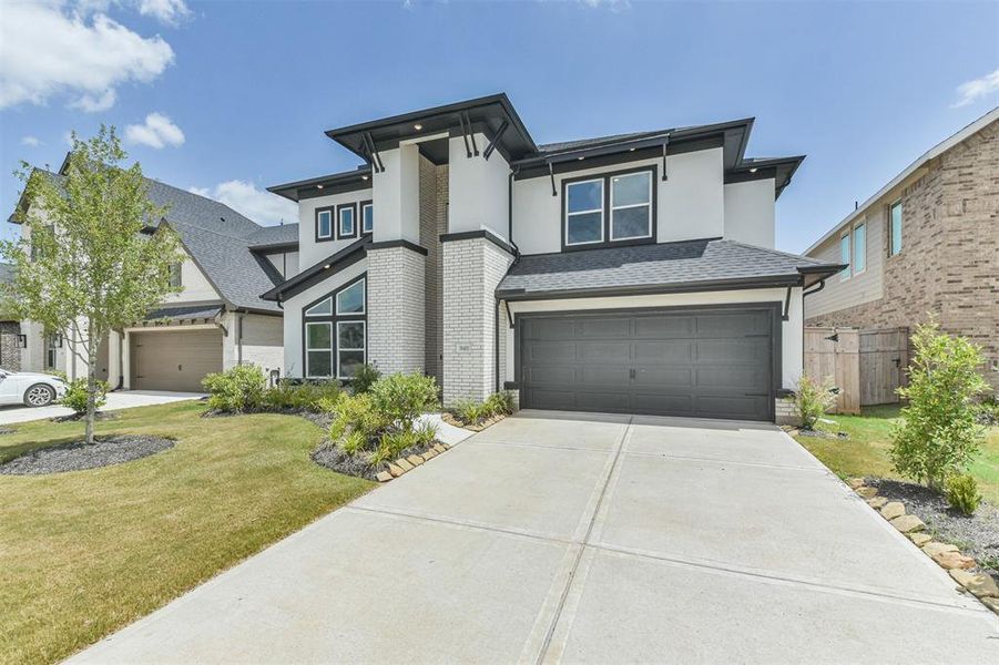 This is a modern two-story home featuring a mix of brick and siding exterior, a double garage, and contemporary windows.