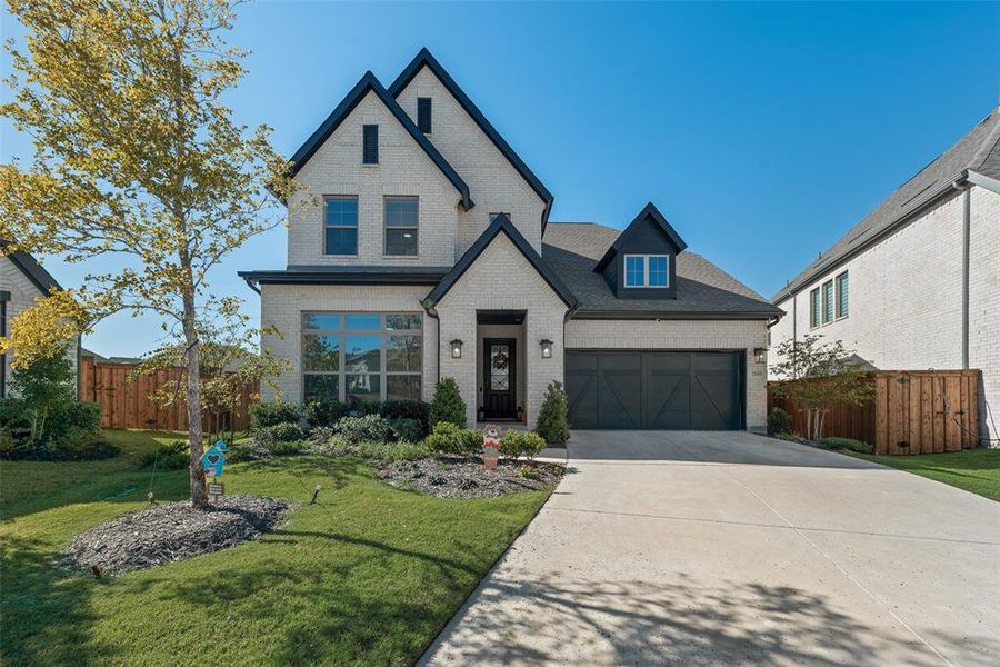 View of front of house with brick siding, driveway, a garage, and a shingled roof