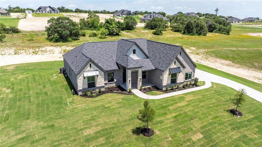 French country inspired facade featuring stone siding, a front lawn, a shingled roof, and a residential view French country inspired facade featuring stone siding, a front lawn, a shingled roof, and a residential view