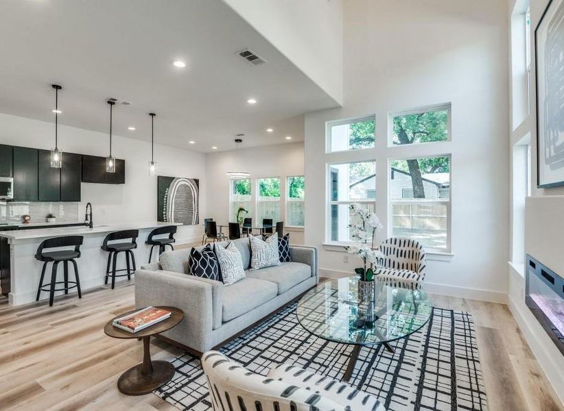 Living room with light wood-type flooring, a wealth of natural light, and a high ceiling