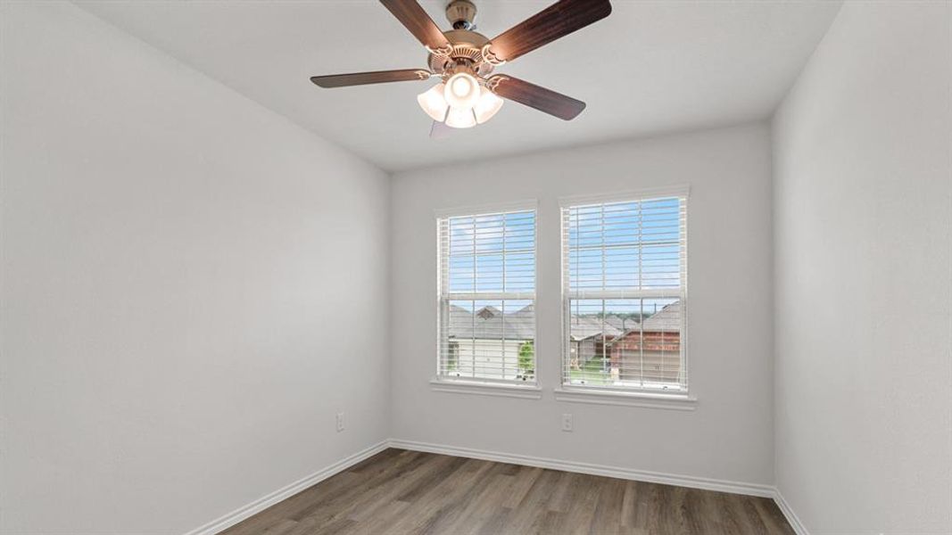 Room featuring wood-finish flooring, white walls, and a ceiling fan with integrated lighting Room featuring wood-finish flooring, white walls, and a ceiling fan with integrated lighting