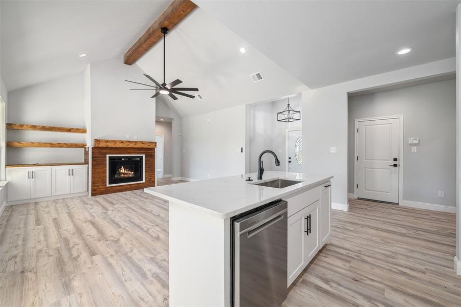 Kitchen with stainless steel dishwasher, light wood-style flooring, ceiling fan, white cabinets, and light stone counters Kitchen with stainless steel dishwasher, light wood-style flooring, ceiling fan, white cabinets, and light stone counters