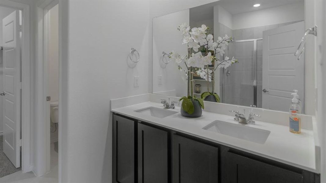Dual vanity with undermount sinks, white countertop, dark wood-finish cabinetry, and a large wall-mounted mirror