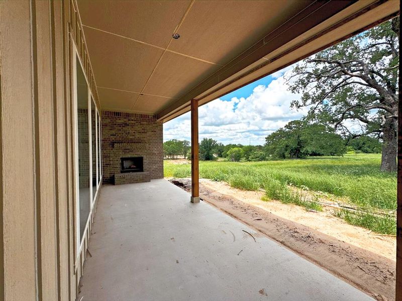 View of patio with an outdoor brick fireplace