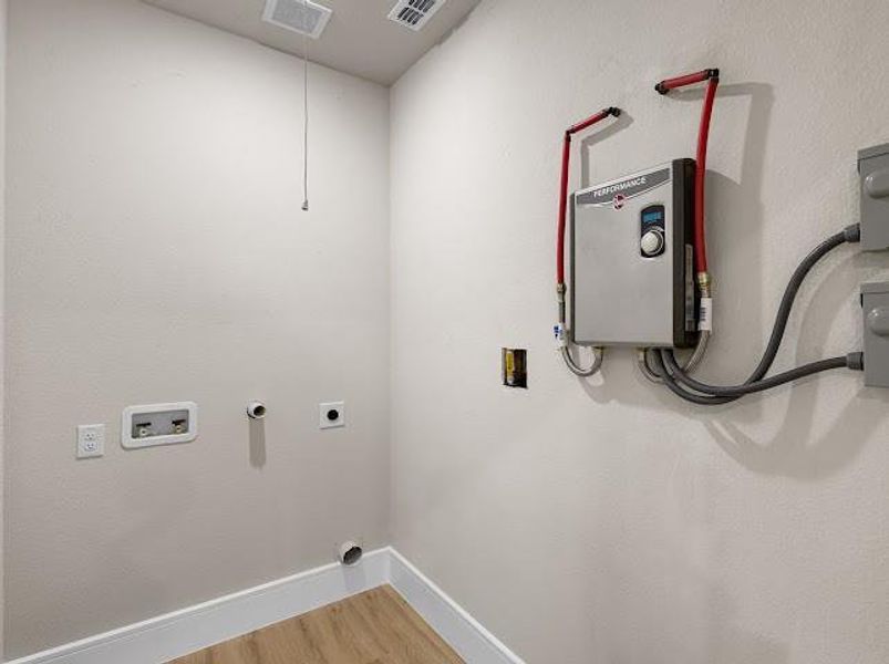 Laundry area with wood finished floors, hookup for an electric dryer, washer hookup, and tankless water heater Laundry area with wood finished floors, hookup for an electric dryer, washer hookup, and tankless water heater