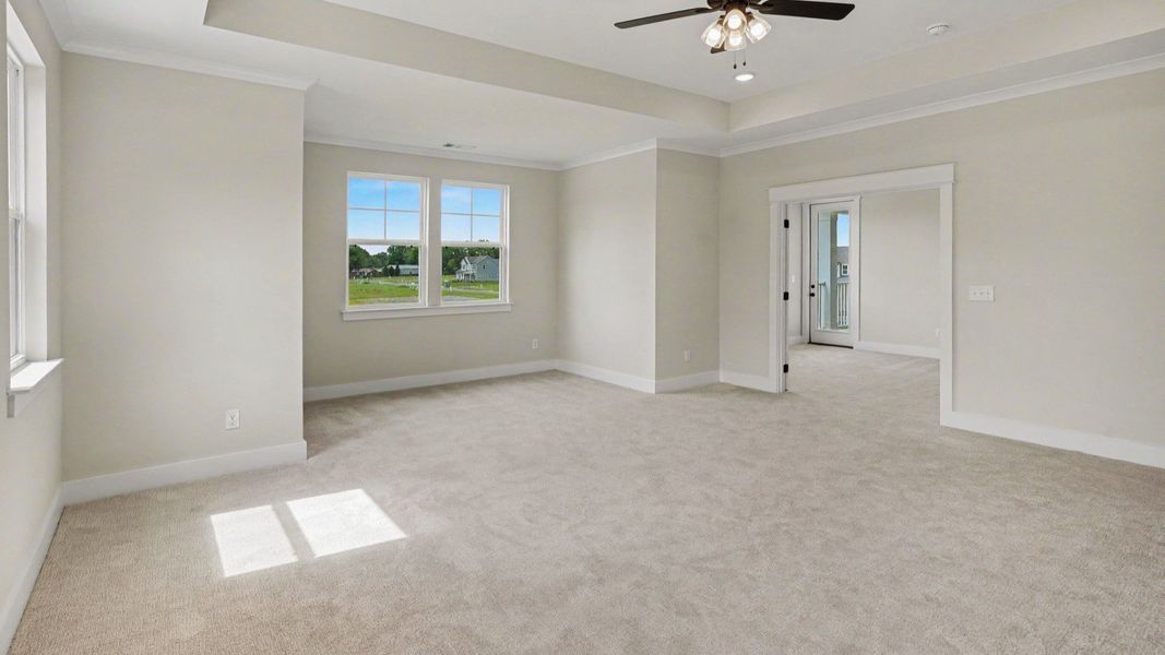 Primary suite with tray ceiling, ceiling fan, and carpet Primary suite with tray ceiling, ceiling fan, and carpet