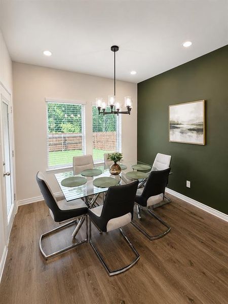 Dining area featuring wood-finish flooring, recessed lighting, and a modern chandelier