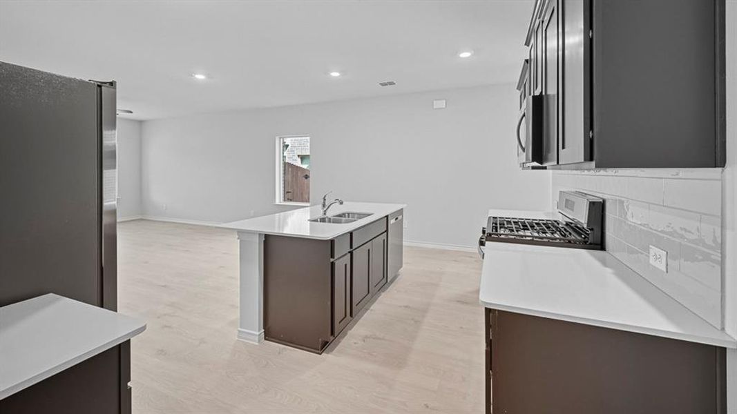 Kitchen featuring appliances with stainless steel finishes, a kitchen island with sink, recessed lighting, light stone countertops, and open floor plan
