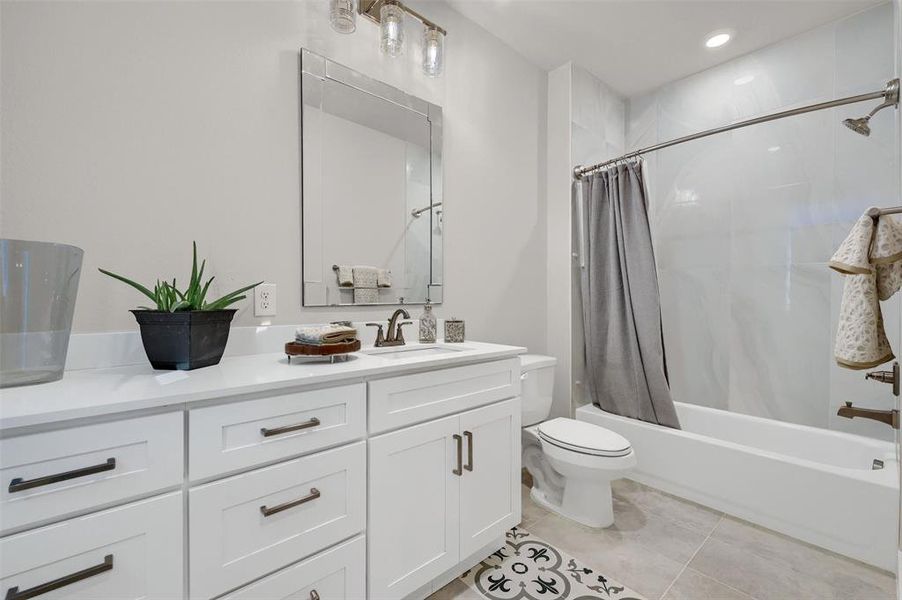 Full bathroom with shower / bath combo with shower curtain, toilet, tile patterned floors, and vanity