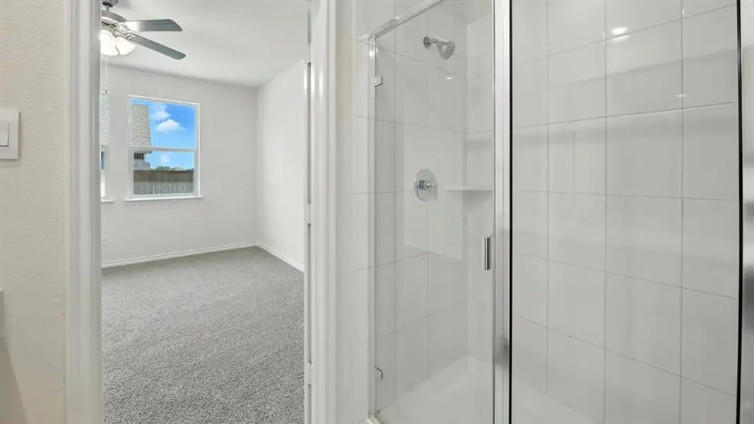 Full bathroom with light colored carpet, a shower stall, and a ceiling fan