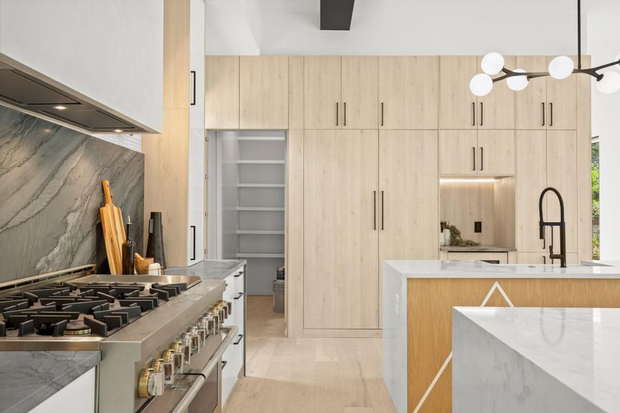 Kitchen featuring light wood finish cabinetry, double oven range, light stone counters, modern cabinets, and light wood-type flooring
