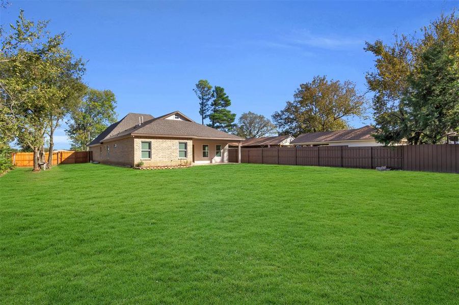 Rear view of house featuring a fenced backyard, a patio area, brick siding, and roof with shingles