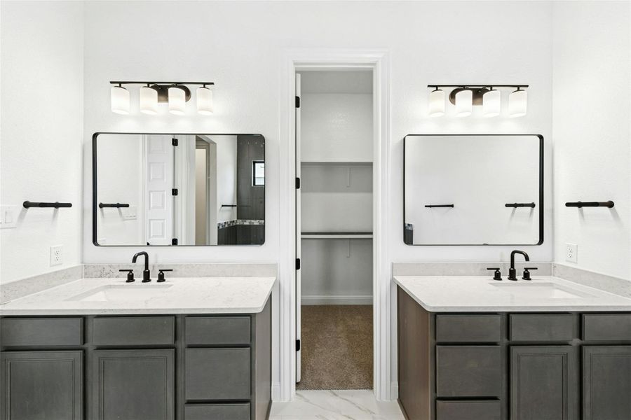 Full bathroom featuring two vanities, a spacious closet, and light marble finish flooring