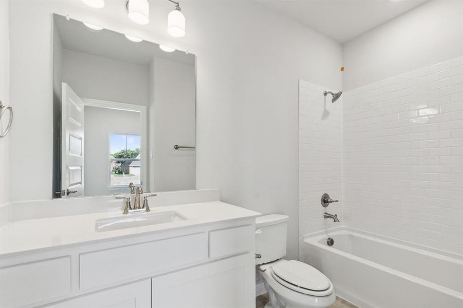 Full bathroom with vanity, tiled shower / bath combo, and toilet