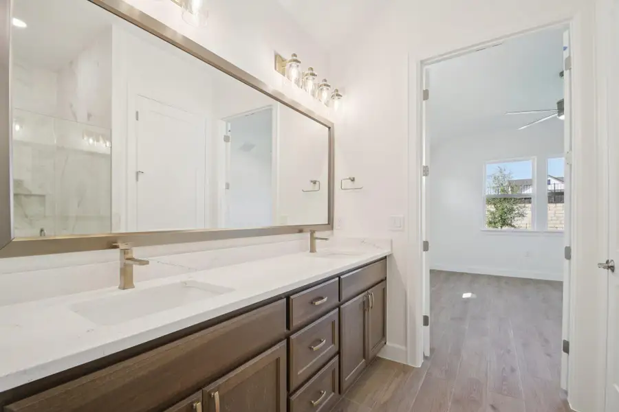 Bathroom with light wood-type flooring, a marble finish shower, double vanity, and ceiling fan