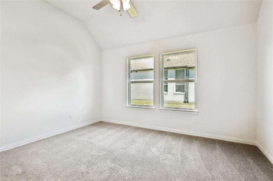 Carpeted empty room with ceiling fan and vaulted ceiling