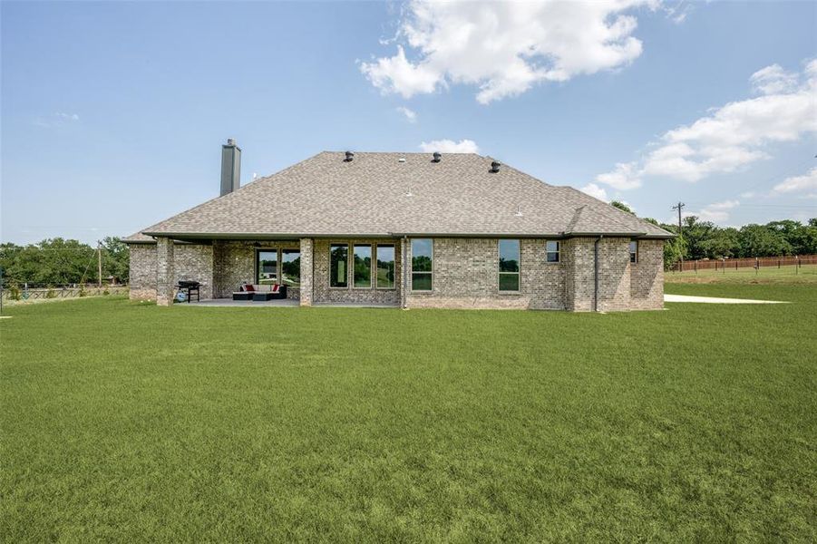 Back of property featuring a lawn and a patio area