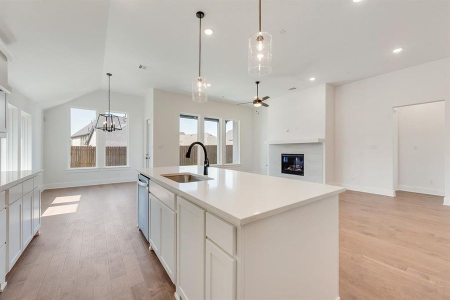 Kitchen with decorative light fixtures, open floor plan, white cabinetry, light wood finished floors, and an island with sink Kitchen with decorative light fixtures, open floor plan, white cabinetry, light wood finished floors, and an island with sink