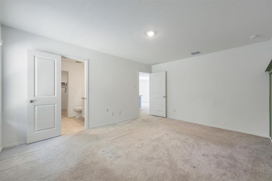 Carpeted room with a neutral color palette, featuring a recessed light fixture and a white paneled door
