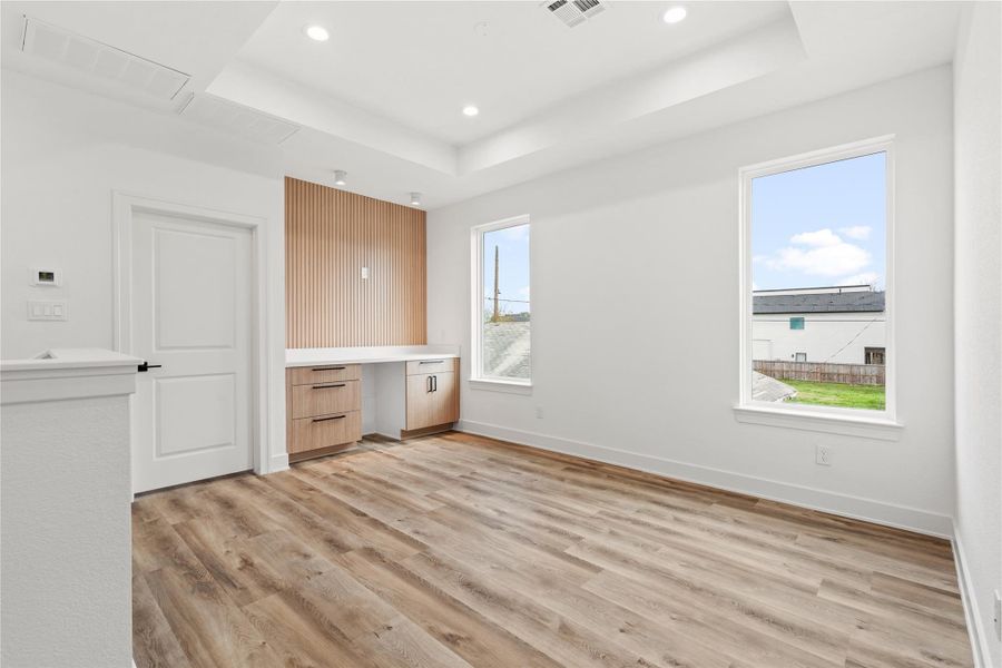 Bright upstairs flex space with vaulted ceilings, large windows, and a built-in desk area.