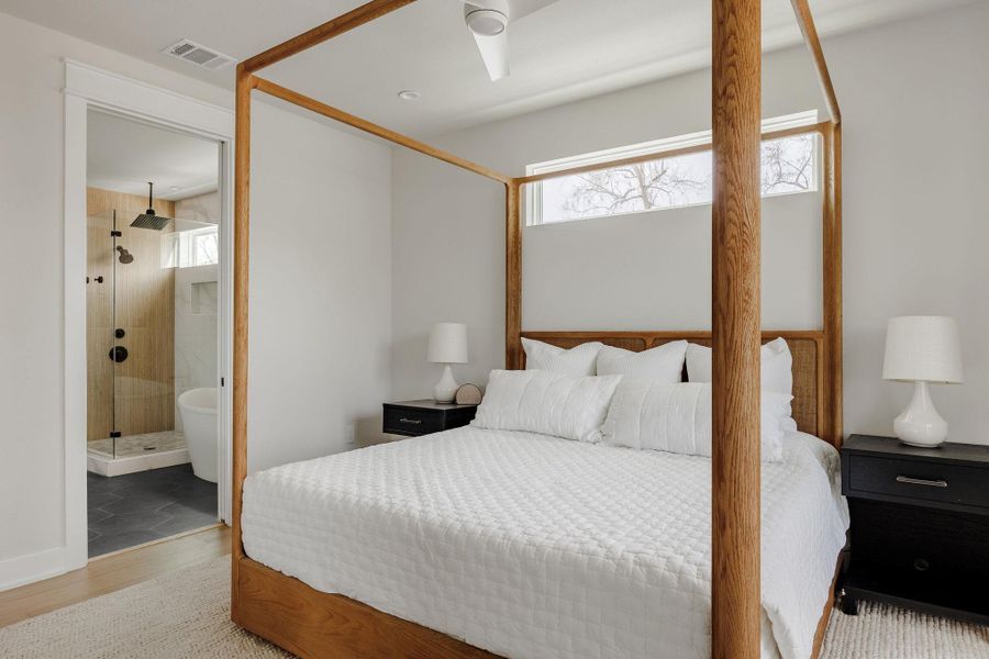 Bedroom with light wood-style floors, ensuite bathroom, and ceiling fan