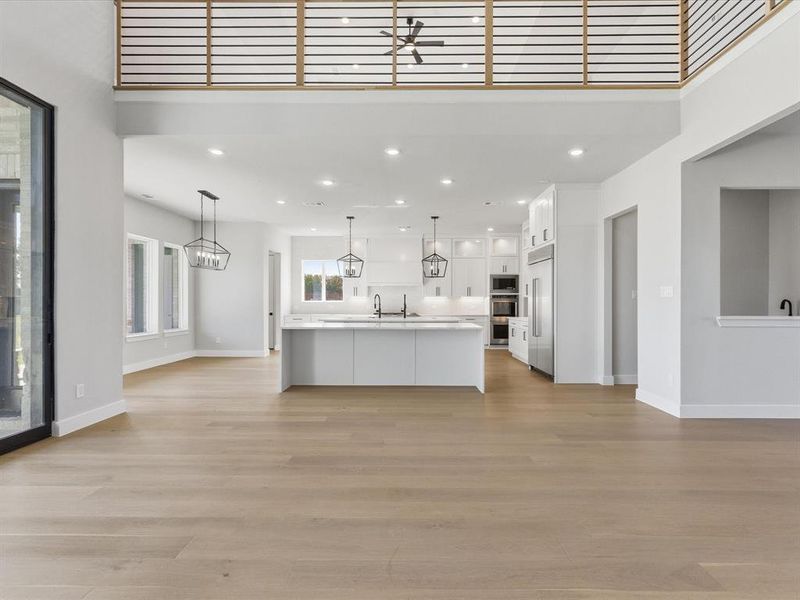 Kitchen featuring open floor plan, white cabinets, light countertops, recessed lighting, and hanging light fixtures