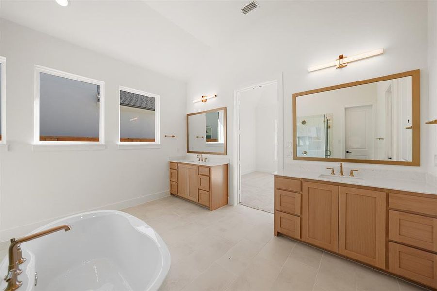 Full bathroom featuring two vanities, a freestanding tub, a shower stall, and lofted ceiling Full bathroom featuring two vanities, a freestanding tub, a shower stall, and lofted ceiling