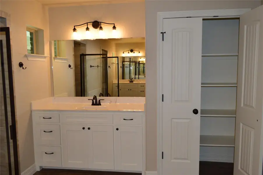 Full bath with a stall shower, vanity, and a closet