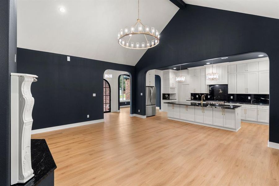 Kitchen featuring arched walkways, a chandelier, decorative light fixtures, white cabinets, and decorative backsplash