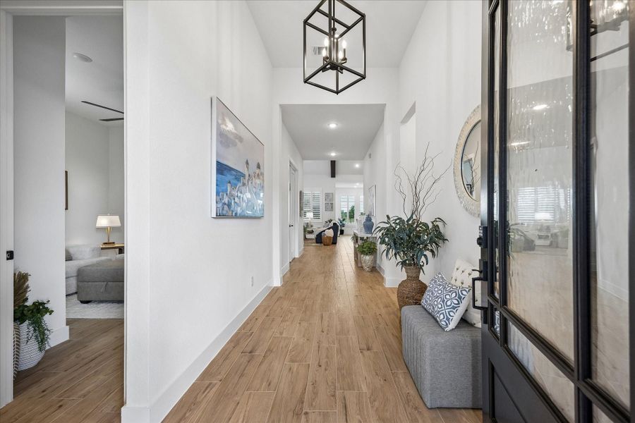 A welcoming, wide entry hallway showcases beautiful wood-plank tile flooring that flows seamlessly into the main living area and continues into the secondary bedroom, creating a warm and cohesive design throughout the home.