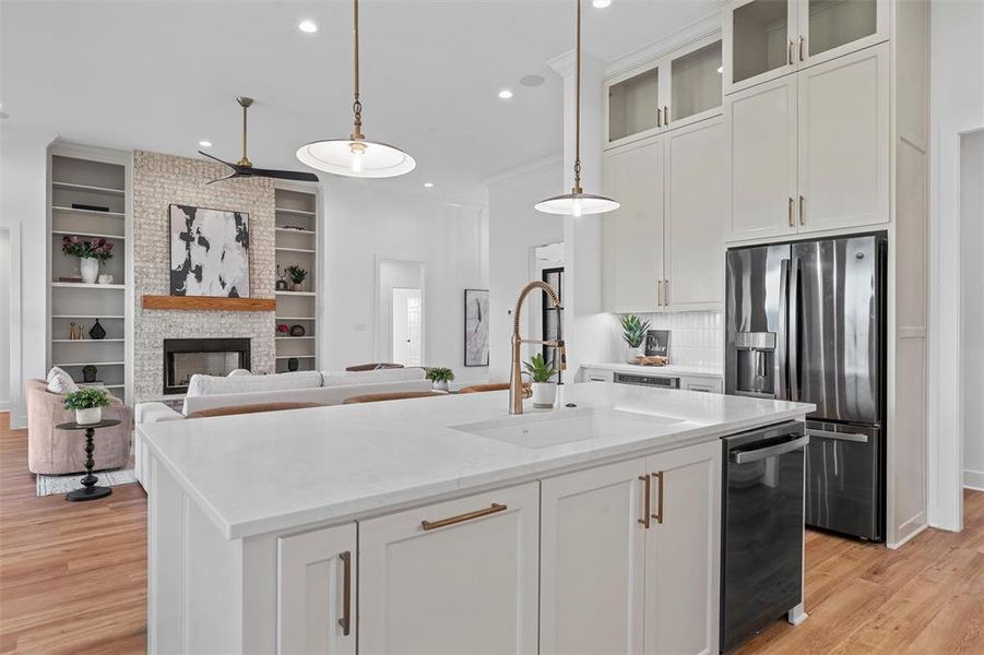 Kitchen with dishwasher, stainless steel refrigerator with ice dispenser, light wood-style flooring, recessed lighting, and an island with sink