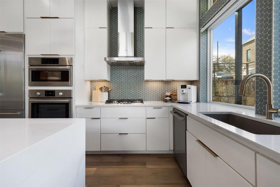 Kitchen featuring stainless steel appliances, light stone counters, white cabinets, dark wood finished floors, and decorative backsplash