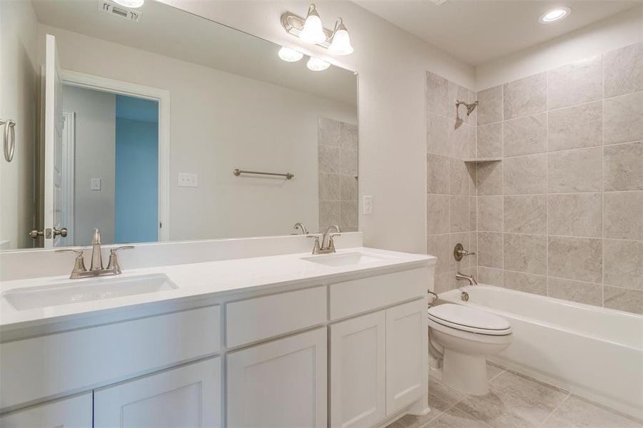 Full bathroom featuring vanity, toilet, tiled shower / bath combo, and tile patterned flooring