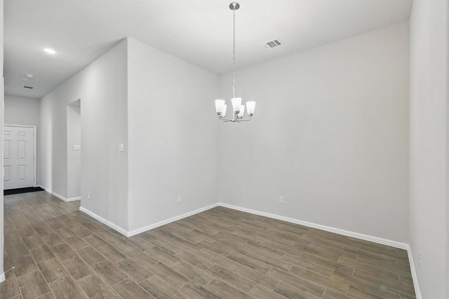 Empty room with wood finished floors, a chandelier, and recessed lighting Empty room with wood finished floors, a chandelier, and recessed lighting