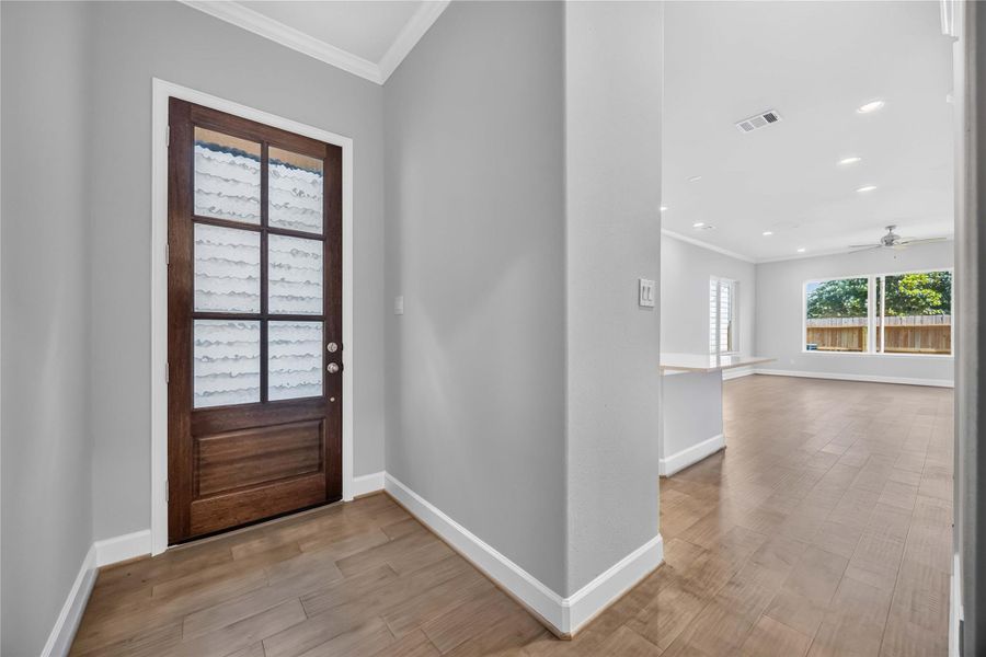 First Impressions Done Right – A custom wood-and-glass front door opens onto hardwood floors that carry you straight into the open living space beyond.