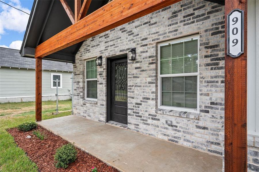 View of exterior entry featuring a patio area and brick siding