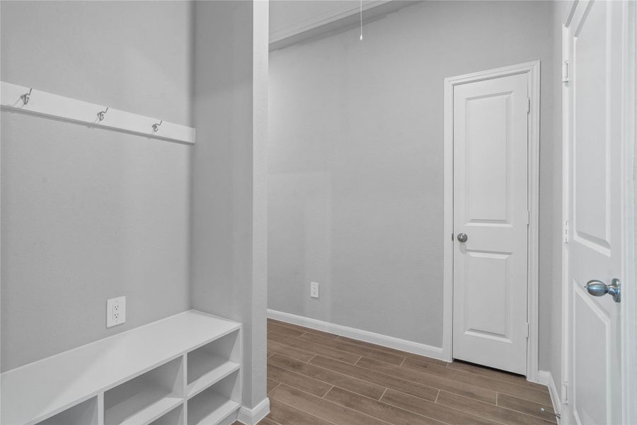 This dedicated area features a custom built-in bench with hooks, perfect for organizing coats, bags, and shoes right off the main hallway, keeping the rest of the home tidy.