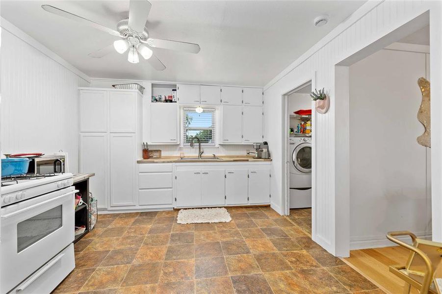 Kitchen featuring stone finish floors, white gas range oven, white cabinets, light countertops, and ornamental molding Kitchen featuring stone finish floors, white gas range oven, white cabinets, light countertops, and ornamental molding